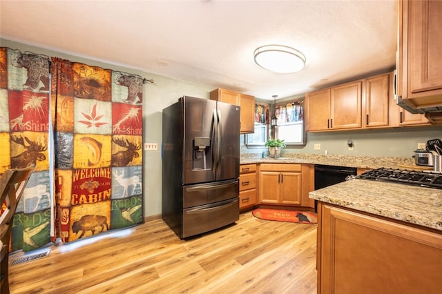 kitchen with black dishwasher, hanging light fixtures, light hardwood / wood-style floors, light stone counters, and stainless steel refrigerator with ice dispenser