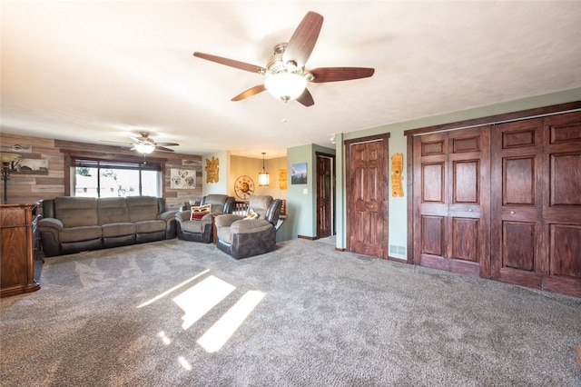 living room featuring wooden walls, carpet flooring, and ceiling fan