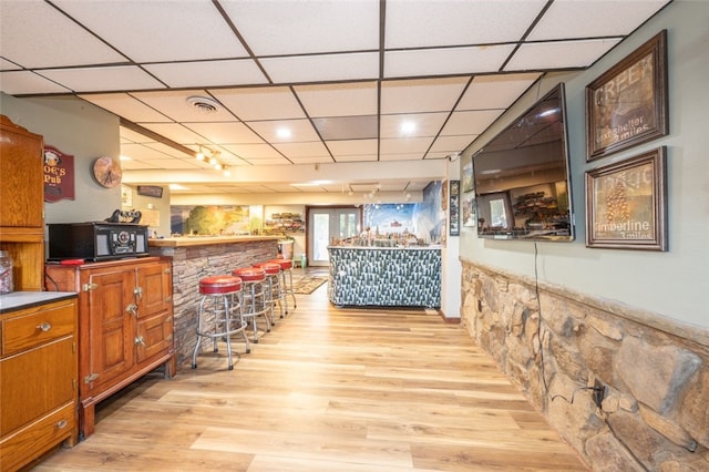 bar featuring a paneled ceiling and light hardwood / wood-style flooring