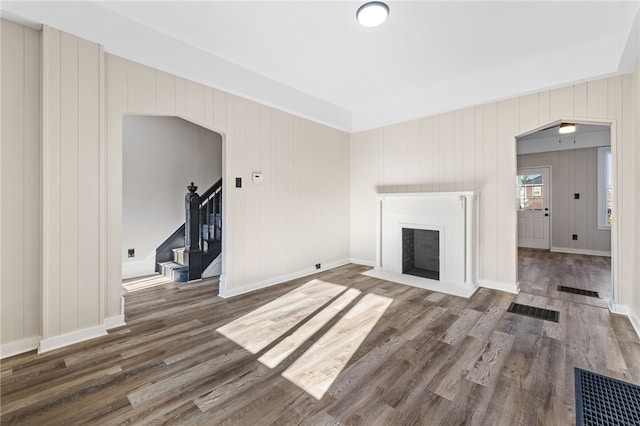 unfurnished living room with dark hardwood / wood-style floors and wood walls