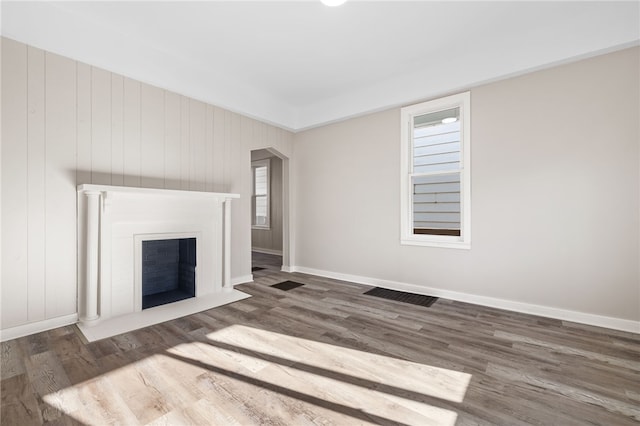 unfurnished living room with wood walls and dark hardwood / wood-style flooring