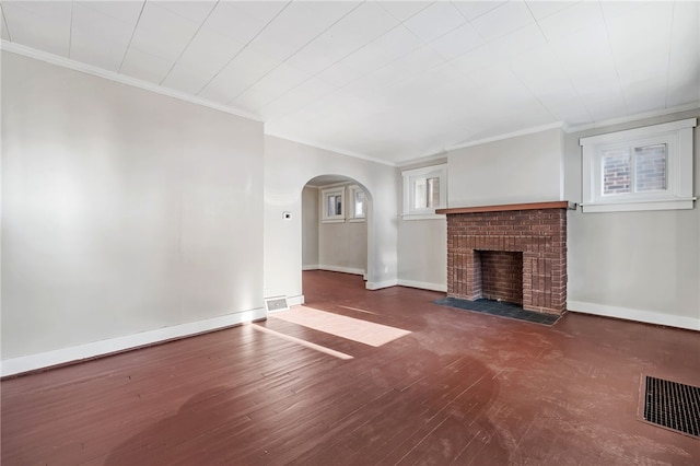 unfurnished living room featuring dark wood-type flooring, a brick fireplace, crown molding, and plenty of natural light