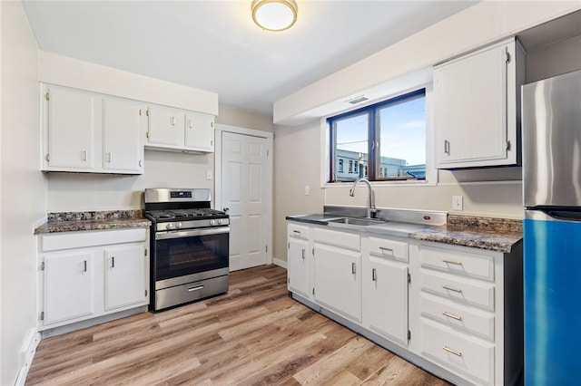 kitchen featuring sink, appliances with stainless steel finishes, light wood-type flooring, and white cabinets