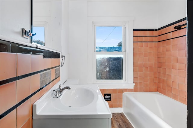 bathroom with a bathtub, tile walls, sink, and hardwood / wood-style floors