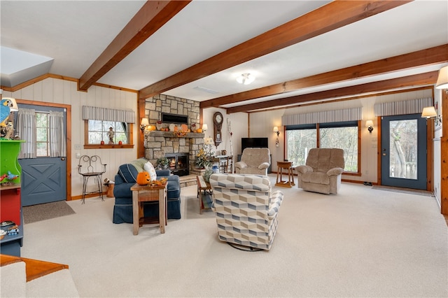 living room with carpet, a stone fireplace, and beamed ceiling