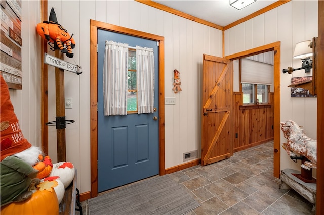 entrance foyer featuring wooden walls, crown molding, and a wealth of natural light