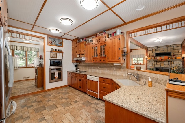 kitchen featuring kitchen peninsula, appliances with stainless steel finishes, tasteful backsplash, ornamental molding, and sink