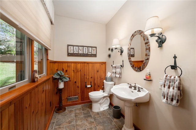 bathroom with wood walls and toilet