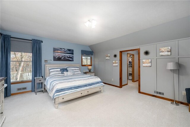 bedroom featuring multiple windows, a walk in closet, carpet floors, and vaulted ceiling