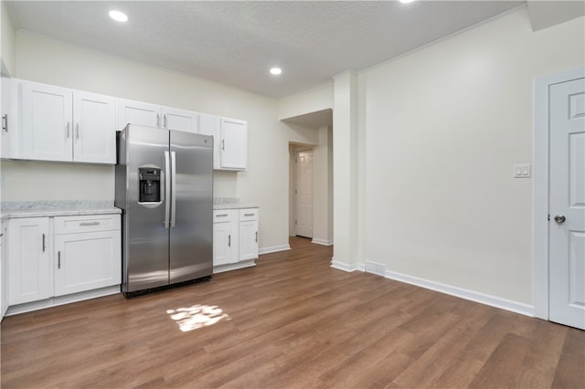 kitchen featuring white cabinetry, stainless steel refrigerator with ice dispenser, a textured ceiling, and light wood-type flooring