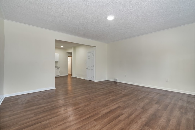 spare room with a textured ceiling and dark hardwood / wood-style flooring