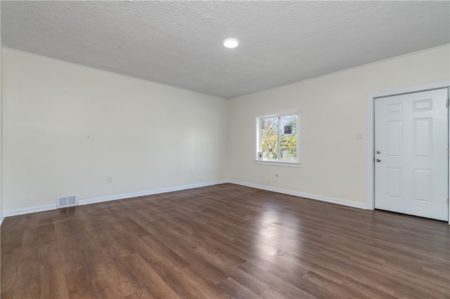 empty room with dark hardwood / wood-style floors and a textured ceiling