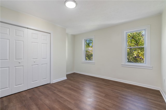 unfurnished bedroom with multiple windows and dark hardwood / wood-style floors