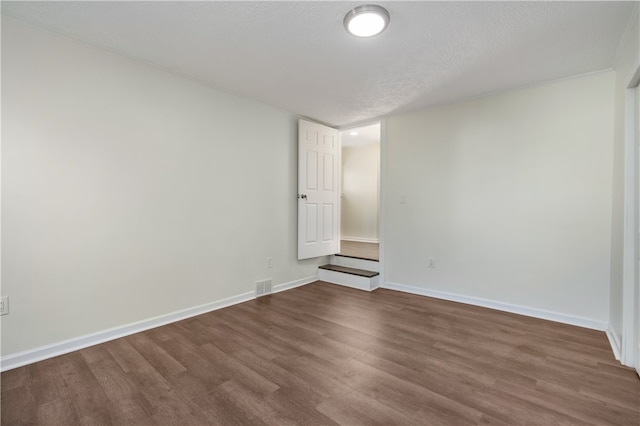 spare room with a textured ceiling and dark wood-type flooring