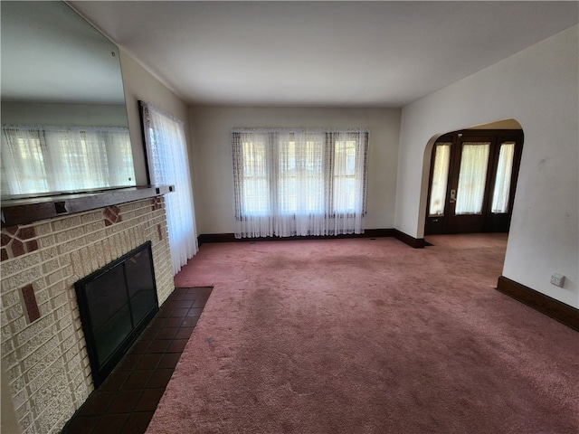 unfurnished living room featuring a brick fireplace and dark colored carpet