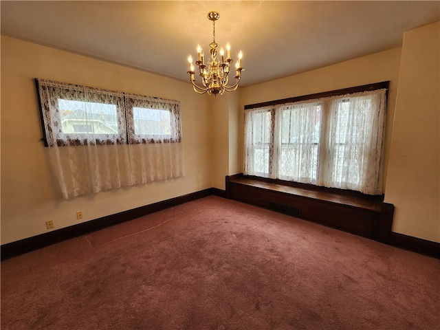 spare room featuring carpet flooring and an inviting chandelier