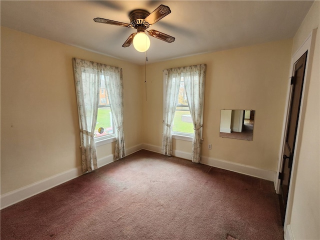 empty room featuring ceiling fan and dark colored carpet