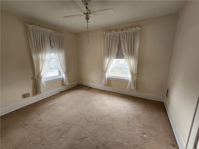 spare room featuring a wealth of natural light, carpet flooring, and ceiling fan