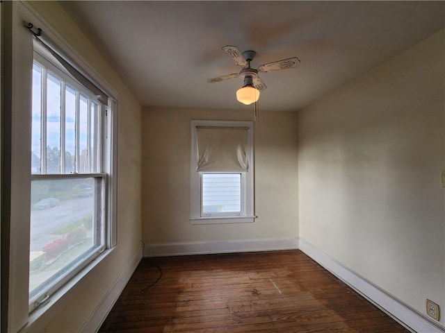 spare room with a wealth of natural light, dark hardwood / wood-style floors, and ceiling fan