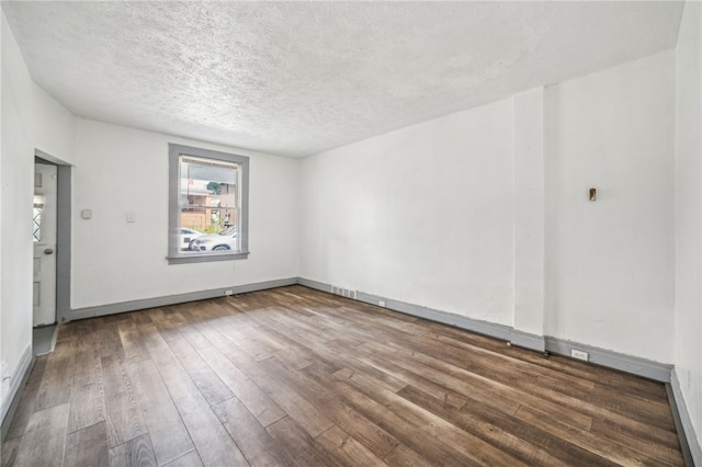 empty room with dark hardwood / wood-style floors and a textured ceiling