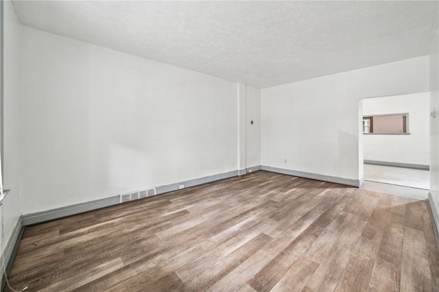 unfurnished room with hardwood / wood-style floors and a textured ceiling