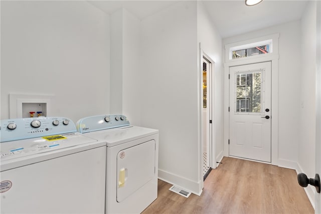 laundry area featuring washer and clothes dryer and light hardwood / wood-style flooring