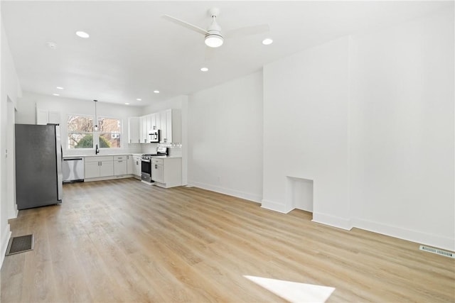 unfurnished living room featuring sink, light hardwood / wood-style flooring, and ceiling fan