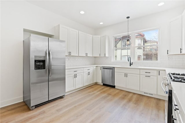 kitchen featuring sink, white cabinetry, decorative light fixtures, light hardwood / wood-style flooring, and stainless steel appliances