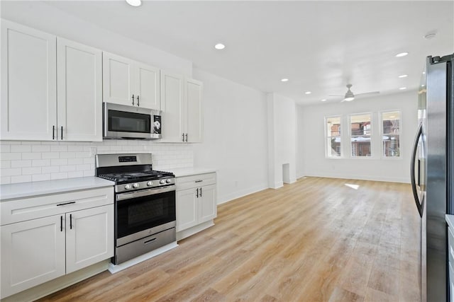 kitchen featuring white cabinetry, decorative backsplash, ceiling fan, stainless steel appliances, and light hardwood / wood-style flooring