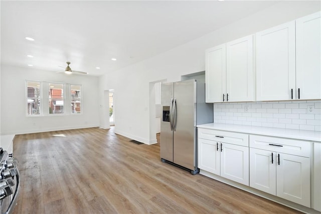 kitchen with white cabinets, backsplash, ceiling fan, stainless steel appliances, and light hardwood / wood-style flooring