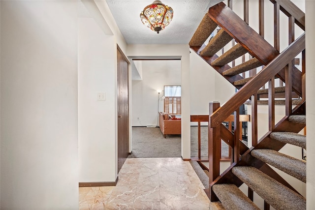 staircase featuring a textured ceiling and carpet flooring