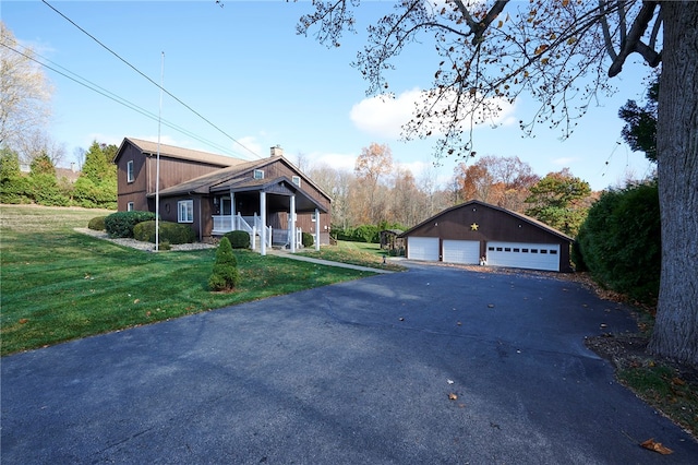 view of front of house with a garage, a front lawn, and an outbuilding