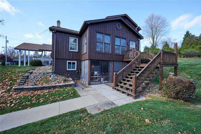 back of house featuring a wooden deck and a lawn