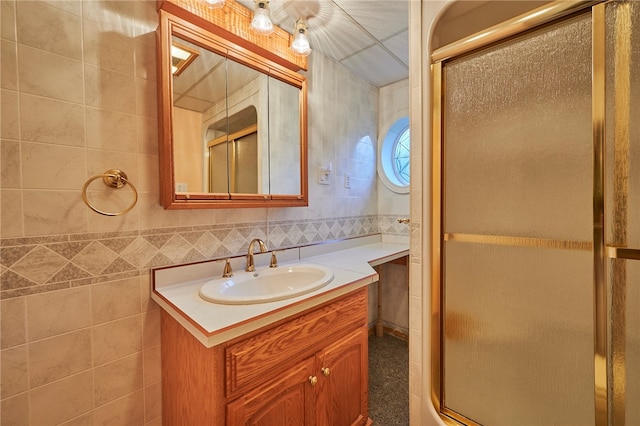 bathroom with vanity, tile walls, and a shower with shower door