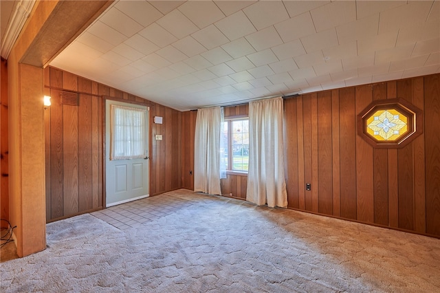 foyer entrance featuring wood walls, vaulted ceiling, and light colored carpet