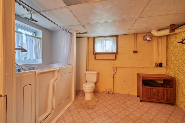 bathroom featuring a drop ceiling, a shower with shower curtain, and toilet