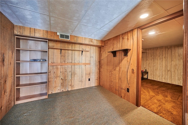 interior space featuring wooden walls and carpet