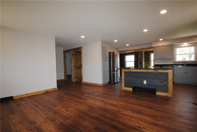 kitchen featuring gray cabinets, dark wood-type flooring, a healthy amount of sunlight, and stainless steel refrigerator