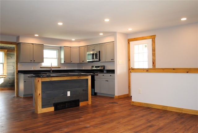 kitchen featuring a center island, stainless steel appliances, dark wood-type flooring, and gray cabinetry