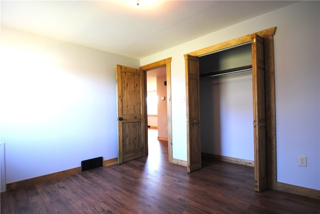 unfurnished bedroom featuring a closet and dark hardwood / wood-style flooring