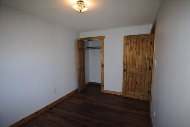 unfurnished bedroom featuring a closet and dark wood-type flooring