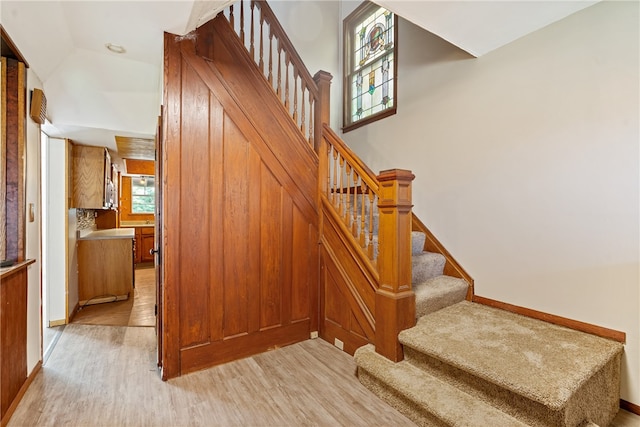 stairway with lofted ceiling, hardwood / wood-style floors, and a healthy amount of sunlight