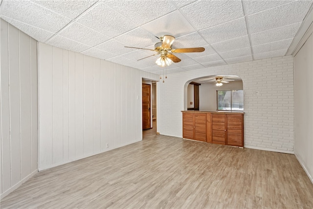 interior space with wood walls, a paneled ceiling, light wood-type flooring, and ceiling fan