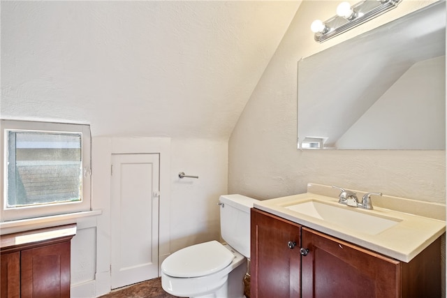 bathroom with toilet, vanity, and vaulted ceiling