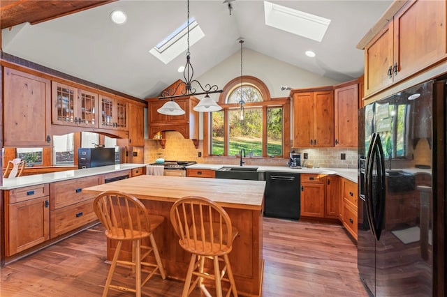 kitchen featuring a center island, black appliances, wood-type flooring, and a skylight