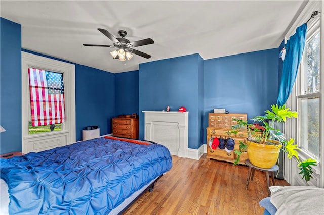 bedroom featuring multiple windows, wood-type flooring, and ceiling fan