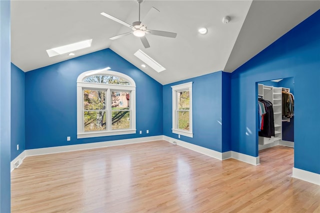 interior space featuring vaulted ceiling with skylight, ceiling fan, light wood-type flooring, and plenty of natural light