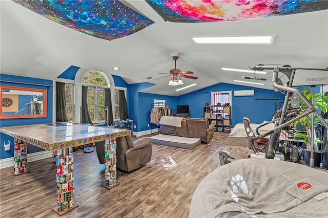 game room featuring a wall mounted AC, hardwood / wood-style floors, vaulted ceiling, and ceiling fan