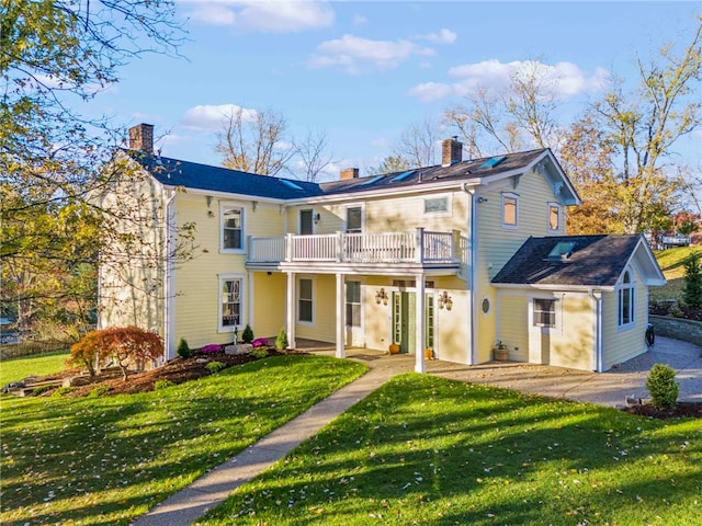 back of house featuring a patio, a lawn, and a balcony