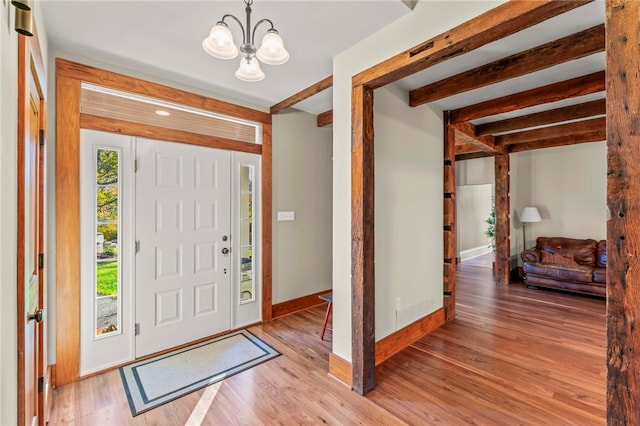 foyer entrance with beamed ceiling, light hardwood / wood-style flooring, and a notable chandelier